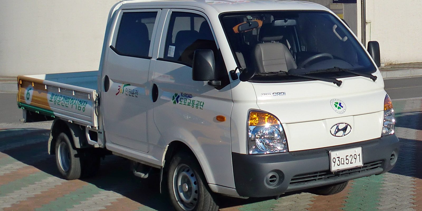 A small flatbed delivery truck parked at a kerb