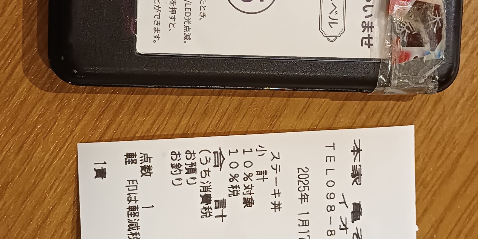 A printed receipt and a phone on a wooden table