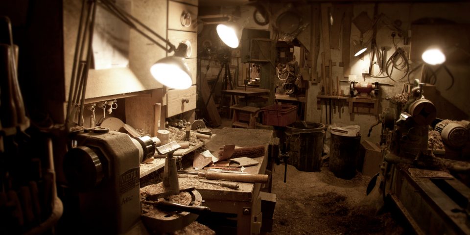 A workbench in a small workshop, lit by task lamps