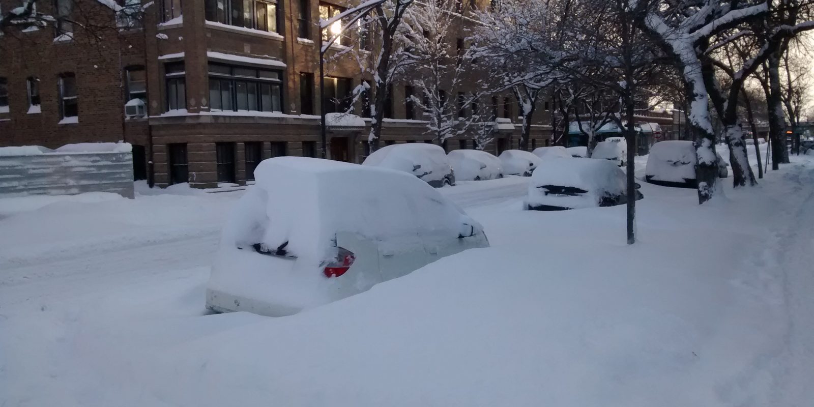 A car buried in snow on a city street